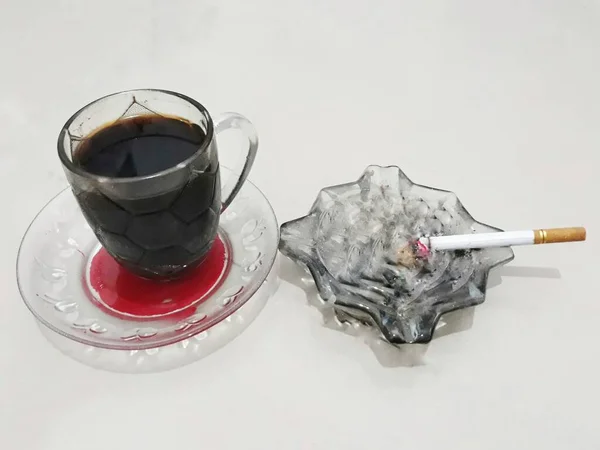 Geleneksel bardakta izole edilmiş siyah kahve ve insanların genellikle her gün tükettiği bir sigara.