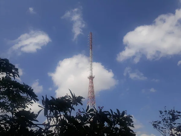 Güneşli mavi gökyüzünde bulutlu telekomünikasyon kulesi