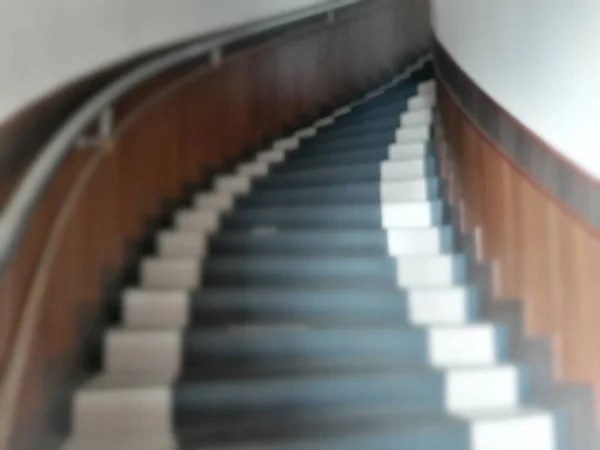 Blurry office twisted staircase from wooden and ceramic with stainless holding hand in defocus background