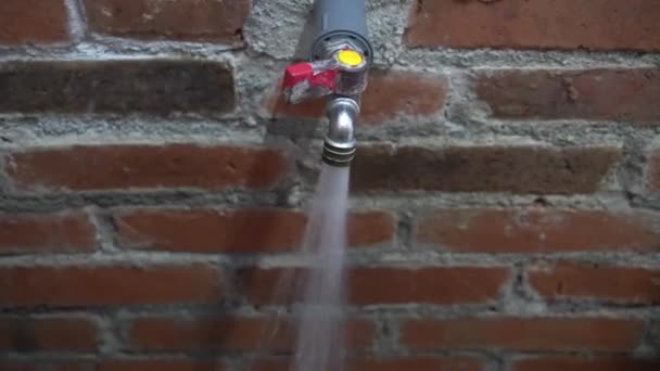 Water Stroomt Uit Een Kraan Die Aan Een Bakstenen Muur — Stockvideo