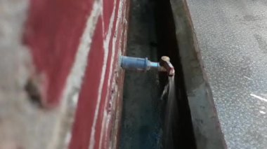 Tuğla bir duvara bağlı musluktan su akıyor.
