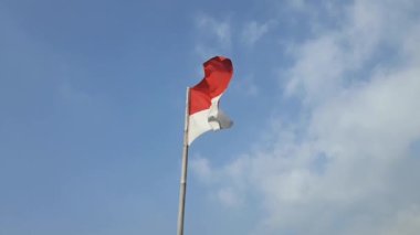 Güneşli bir günde bambu direğinde dalgalanan Endonezya kırmızı ve beyaz bayrağı.