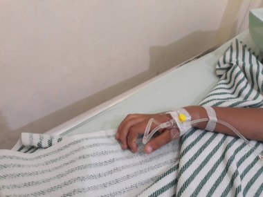 Çocuğun eli, yatağın üstündeki hastane odasında birleşiyor.