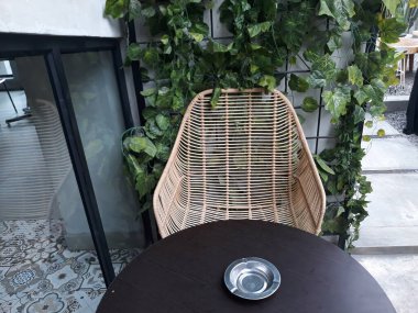 bir kafe masası ve taş zeminli sandalyeler ve duvarlara bitki süslemeleri.