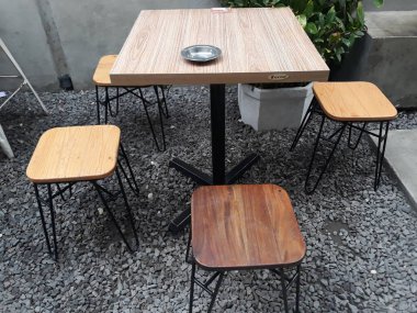 bir kafe masası ve taş zeminli sandalyeler ve duvarlara bitki süslemeleri.