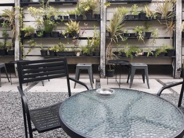 bir kafe masası ve taş zeminli sandalyeler ve duvarlara bitki süslemeleri.