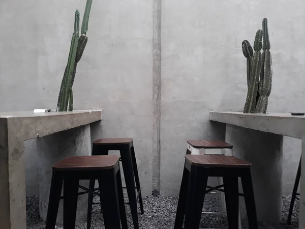 a caf table and chairs with stone floors and plant decorations on the walls