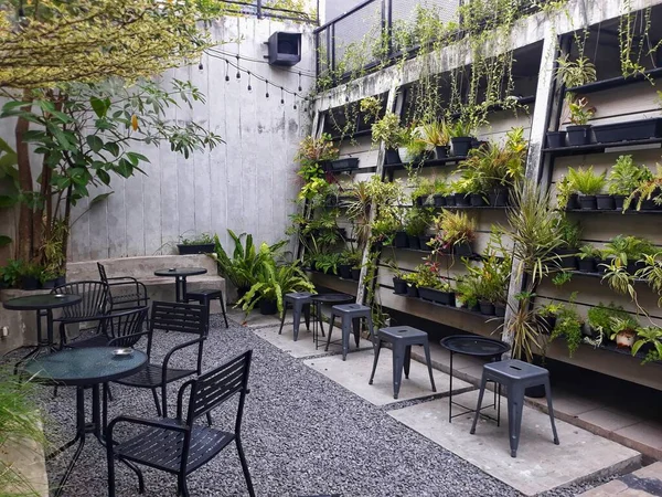 a caf table and chairs with stone floors and plant decorations on the walls