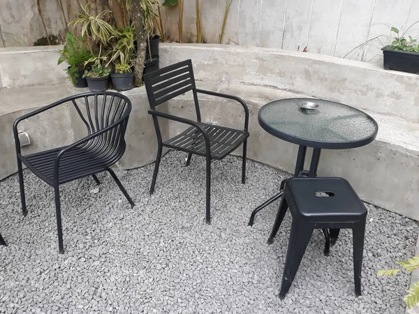 a caf table and chairs with stone floors and plant decorations on the walls