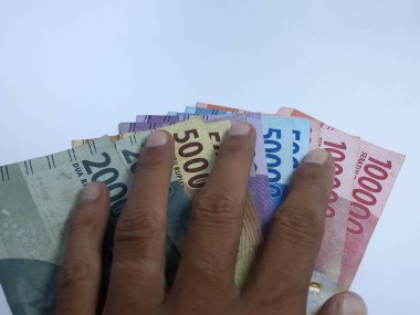 Rupiah 'a ait birkaç banknot, beyaz elin üzerinde izole bir şekilde duruyor. Rupiah Endonezya 'nın para birimidir.