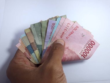 Rupiah 'a ait birkaç banknot, beyaz elin üzerinde izole bir şekilde duruyor. Rupiah Endonezya 'nın para birimidir.