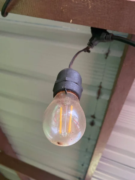 an incandescent light bulb turns off during the day