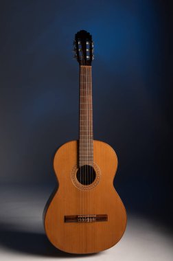Classical guitar upright on a mottled blue background