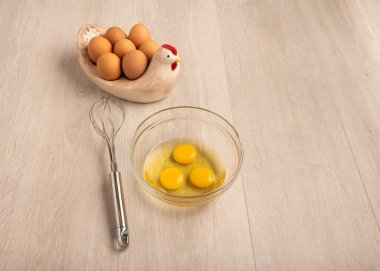 Tabaktaki yumurtalar ve arka planda çırpılmış çırpılmış cam bir kase.