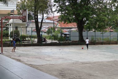 Gorontalo-Indonesia, June 2022 - Children practicing soccer on a basketball court during the day
