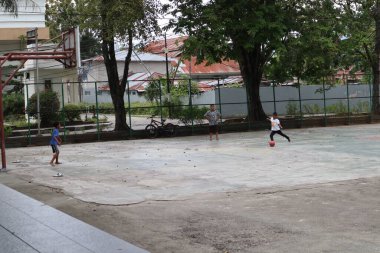 Gorontalo-Indonesia, June 2022 - Children practicing soccer on a basketball court during the day