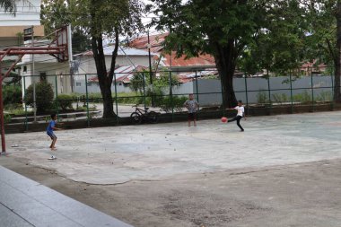 Gorontalo-Indonesia, June 2022 - Children practicing soccer on a basketball court during the day