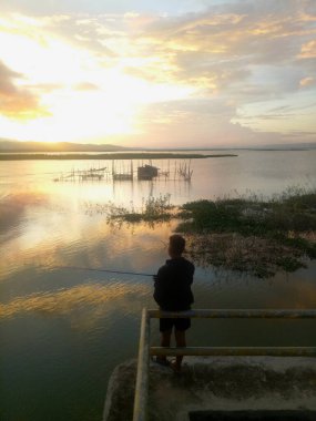 Silhouette of a man fishing in the afternoon. sunset on lake Limboto, Indonesia
