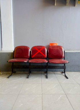 Empty waiting chairs with social distancing signs. Black chair with a symbol on a chair in office during Covid-19 or Coronavirus pandemic.