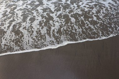 Kumlu sahilde yumuşak bir mavi okyanus dalgası. Arkaplan.