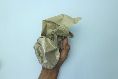 The hand holds a lump of old paper. Isolated on white background.