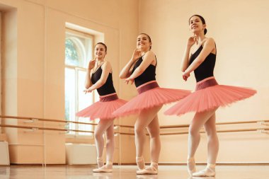 Low angle view of happy ballerinas posing at ballet studio. 