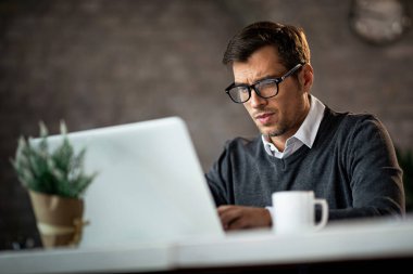 Low angle view of freelance worker using laptop and typing and e-mail while being at work. 