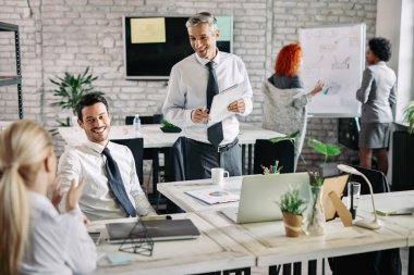 Small group of smiling business people having a meeting in the office and communicating. Focus is on mid adult businessman. 