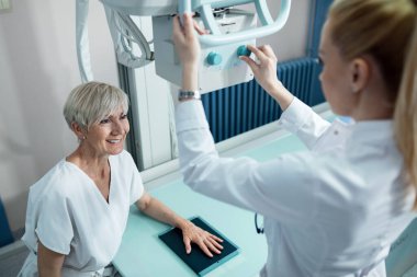 Smiling senior woman undergoing for hand X-ray in the hospital. 