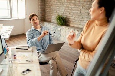 Ofisteki sunumu sırasında meslektaşı ile yeni iş planı hakkında konuşan genç girişimci. 