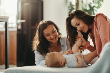 Loving lesbian couple playing with their baby while spending time together at home. 