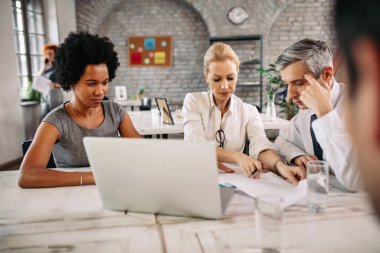 Multi-ethnic group of business people cooperating while working on business plans during a meeting. 