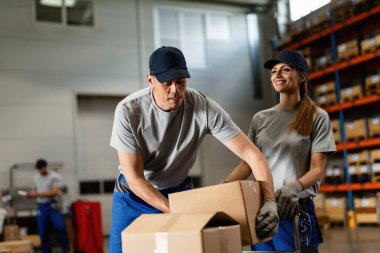 Two workers cooperating while working preparing packages for distribution in a warehouse. 