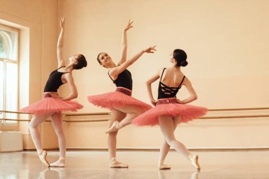 Small group of ballerinas dancing together at ballet studio. 