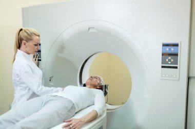 Mature patient and radiologist during MRI scan procedure in medical examination room at clinic. 