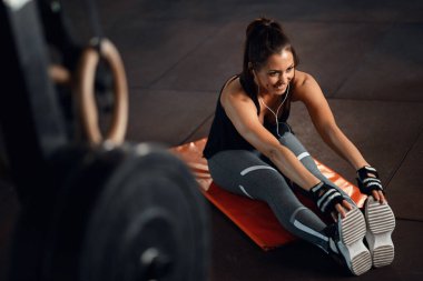 Young sportswoman doing stretching exercises while warming up before sports training in a gym