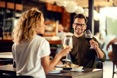 Happy couple enjoying in conversation while drinking wine and eating in a bar. 