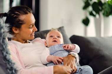 Young happy mother and her baby spending time together and relaxing in the living room. 