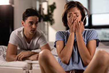 Young woman feeling frustrated while having relationship problems and arguing with her boyfriend in the bedroom. 
