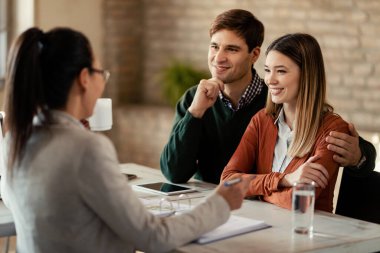 Happy couple talking with their insurance agent on a meeting in the office. 
