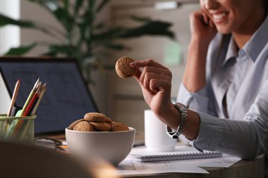 Close up of businesswoman eating cookies on a break in her office. 
