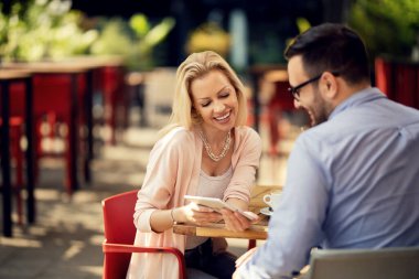 Happy couple using touchpad and reading something on the Internet together in a cafe. Focus is on woman. 