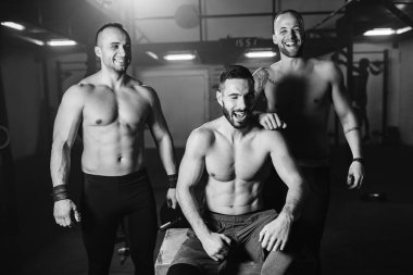 Small group of shitless athletic men laughing and having fun while working out in a gym. 