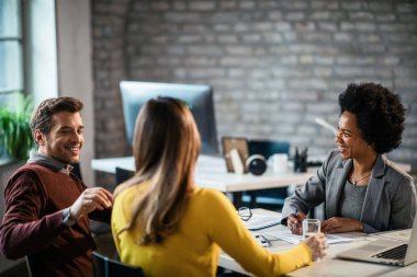 Happy couple communicating with their insurance agent on a meeting in the office. 