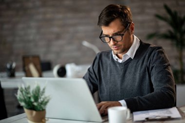 Mid adult businessman working on a computer at his office desk. 