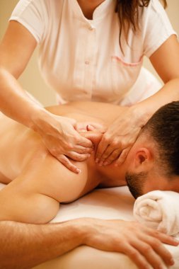 Unrecognizable man having shoulder massage at health spa. 