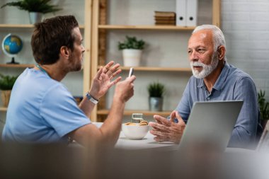 Mature man and his doctor communicating during consultations at doctor's office. Copy space. 