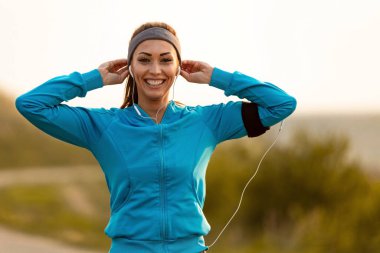 Happy female runner getting ready for jogging in the morning and looking at camera.