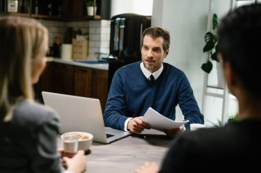 Financial advisor talking to a couple while having consultations at their home. 