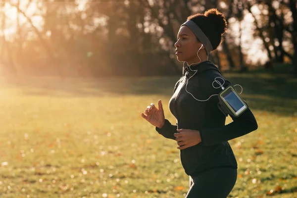 Black athletic woman running while exercising in the park. Copy space.